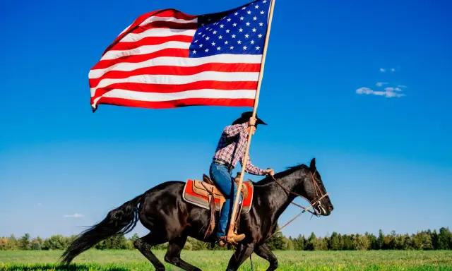 Kowbojka na czarnym koniu niesie flagę USA. To obraz wolności i dzikiego zachodu, pełen ciekawostek o Ameryce.