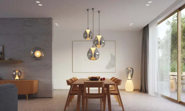 Quel luminaire pour salon salle à manger ? Suspensions modernes au-dessus d'une table en bois, lampe sur pied design et applique murale sphérique créent une ambiance chaleureuse.