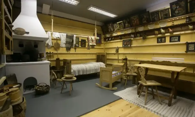Wnętrze izby w muzeum w Szczawnicy: piec, łóżko, kołyska, stół i krzesła.