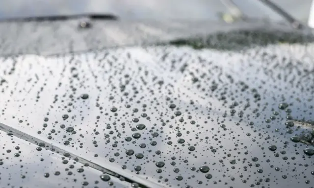 Krople wody na ciemnym lakierze po nałożeniu ceramiki. Efekt perlenia świadczy o hydrofobowości powłoki.