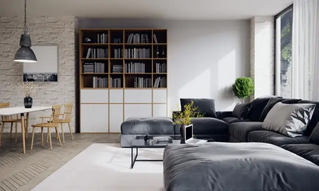Un salon moderne avec un grand canapé d'angle gris foncé, une bibliothèque remplie de livres, une table basse et une table à manger en bois clair.