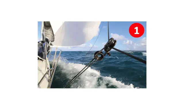 Le fonctionnement poulie est visible sur ce voilier naviguant sur une mer agitée. Les cordages tirent la voile blanche.