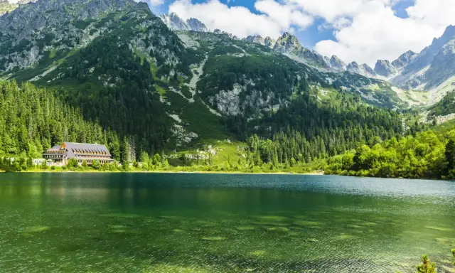 Zielone jeziora w Tatrach, otoczone lasem i majestatycznymi szczytami, z widocznym hotelem nad brzegiem.