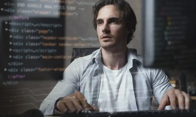 Mężczyzna pracuje nad kodem, tworząc aplikację full stack. W tle widać fragmenty kodu HTML i JavaScript.