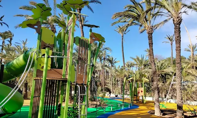 Parque el Palmeral con juegos infantiles coloridos y palmeras altas bajo un cielo azul.