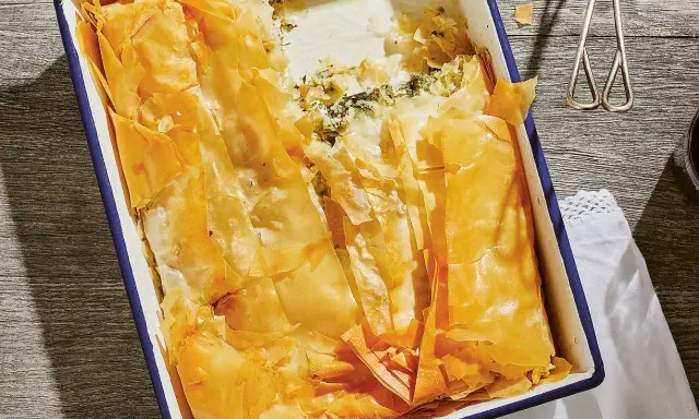 En gyllene, krispig spenatpaj i en blå kantad form. Perfekt för ett spanakopita recept.
