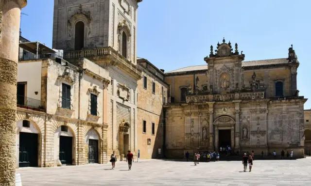 Piazza del Duomo a Lecce, un assaggio di cosa vedere a Lecce in un giorno: la cattedrale barocca e il campanile svettano sotto il sole.