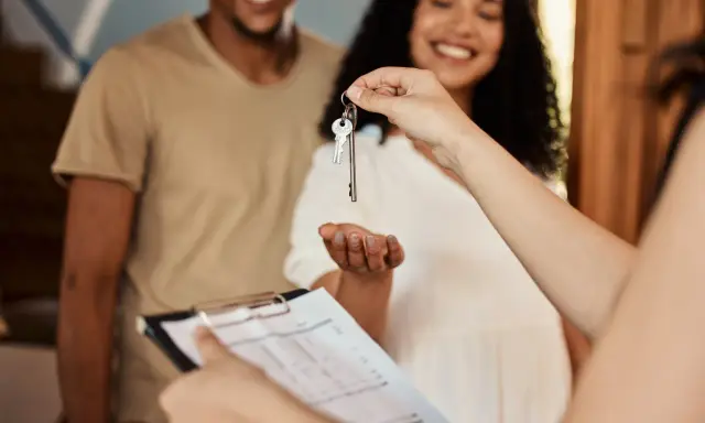 Pareja feliz recibe llaves de su nuevo hogar. Se discute la duración del contrato de alquiler.