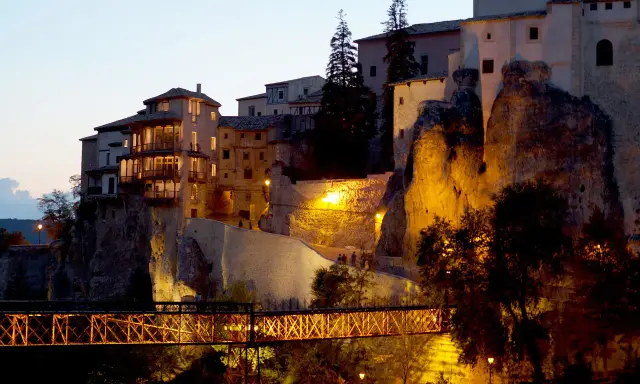 El puente de San Pablo en Cuenca, iluminado de noche, conecta las casas colgantes con la ciudad.