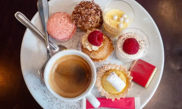 Assortiment de spécialités culinaires parisiennes : macarons, éclairs, tartellettes, verrines et café. Un délice pour les yeux et les papilles.