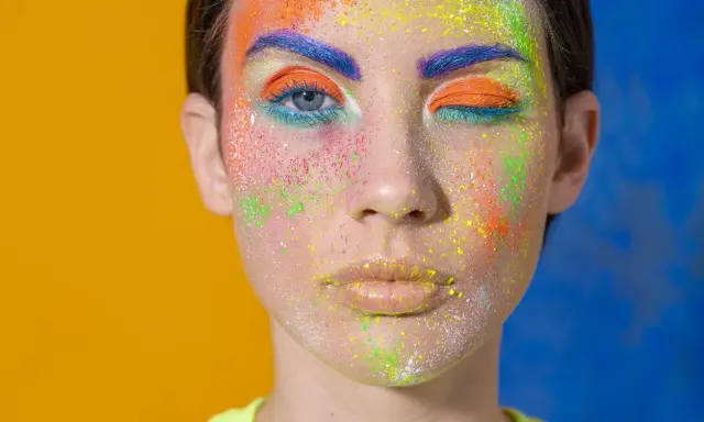 Rostro con maquillaje vibrante y purpurina. ¿Cómo quitar la purpurina de la cara? Este look es un desafío.