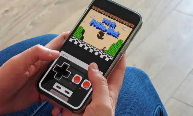 Jouer à Super Mario Bros sur iPhone avec l'émulateur Delta. La manette virtuelle rappelle les consoles d'antan.