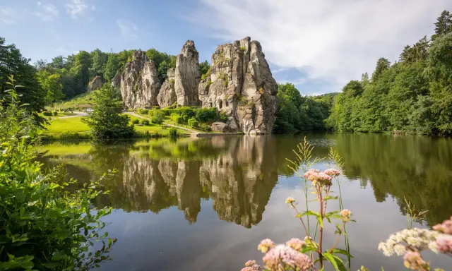 Ein idyllischer See spiegelt die imposanten Externsteine wider. Perfekt für eine entspannte Wanderung in dieser malerischen Landschaft.
