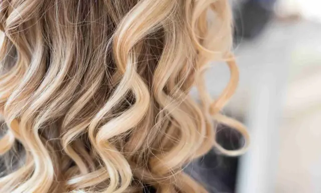 Falujące włosy z pasemkami blond z jasnym brązem, tworzące efekt słonecznych refleksów.