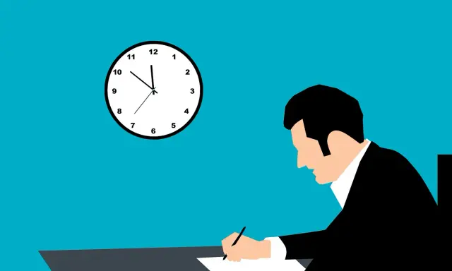 Mann schreibt am Schreibtisch, Uhr zeigt kurz vor 11. Vielleicht eine Kündigung Nachhilfe?