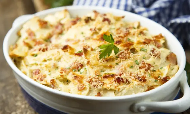 Un plat de tartiflette gratiné, doré et fumant, garni de lardons et de persil. Idéal pour savoir quel vin avec tartiflette.