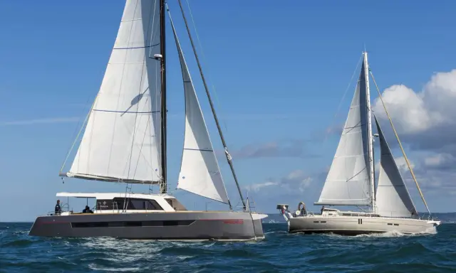 Deux grands voiliers naviguent sur une mer bleue sous un ciel clair.