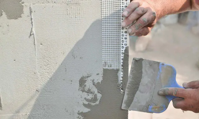 Tynkowanie narożnika z siatką zbrojącą, która chroni ścianę przed deszczem i pęknięciami.