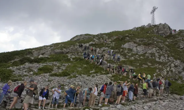 Tłum turystów wspina się na Giewont. Kolejka do wjazdu na szczyt jest długa, a cennik pewnie nie jest tani.