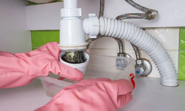 Mains de nettoyage rose démontant le siphon de lavabo bouché. Schéma montage siphon lavabo.