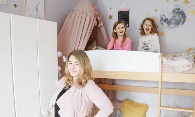 Wesołe dziewczynki w łóżku piętrowym w pokoju dla rodzeństwa. Mama uśmiecha się obok.