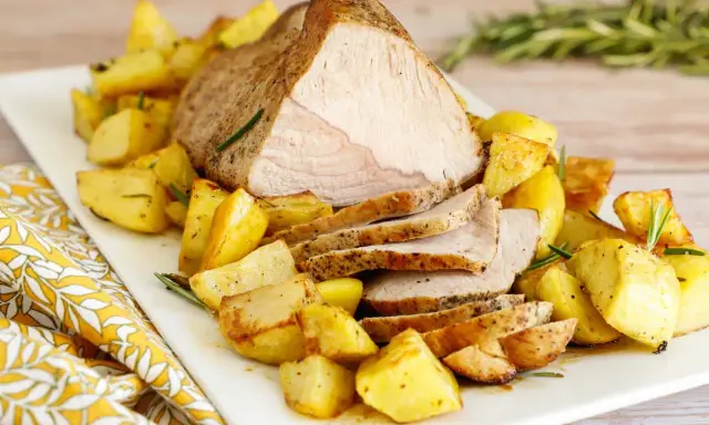 Arrosto di vitello al forno, succulento e dorato, servito con patate arrosto croccanti e profumate al rosmarino.