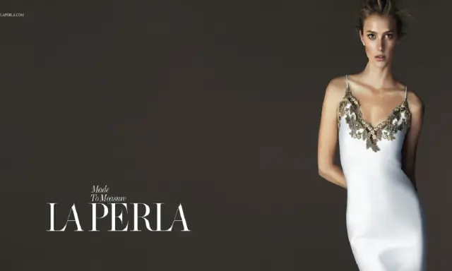 Model in a white slip dress with gold lace trim, with "LA PERLA" logo.
