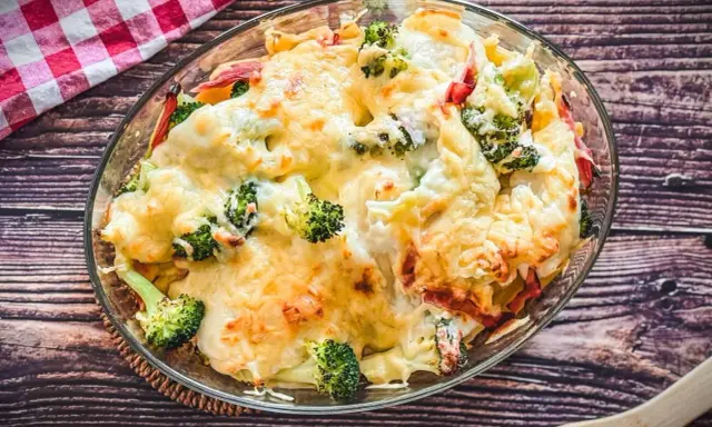 Heißer Brokkoli Nudel Auflauf mit geschmolzenem Käse in einer Glasschüssel, bereit zum Servieren.