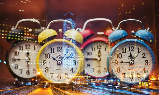 Wiele kolorowych budzików na tle nocnego miasta. 0404 znaczenie czasu, który nieustannie płynie.