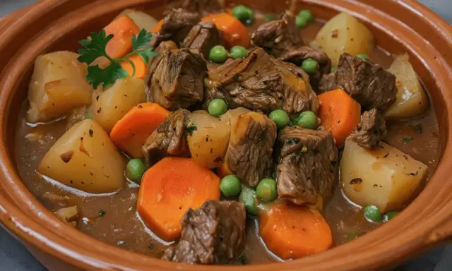Un reconfortante plato de carne guisada con trozos de ternera tierna, patatas, zanahorias y guisantes en una rica salsa.