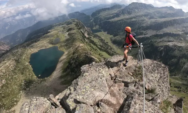 Escursionista in cima a una cresta rocciosa con vista sui laghi di Bombasel e sulle montagne circostanti.