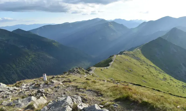 Widok na pasmo górskie Tatr z zielonymi zboczami i kamienistym szlakiem.