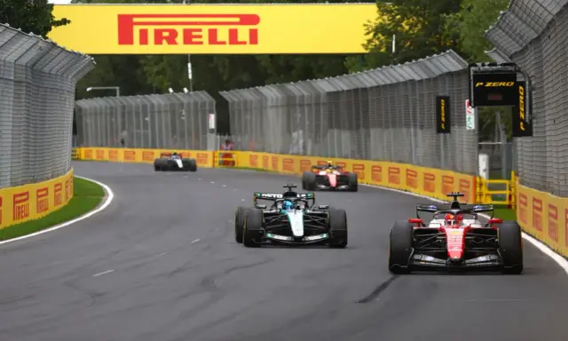 Coches de Fórmula 1 compiten en una curva, con el cartel de Pirelli al fondo. ¡Emocionantes noticias de Fórmula 1!