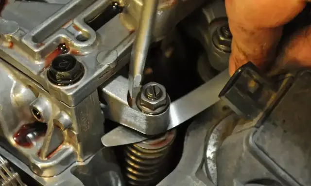 Precyzyjna regulacja zaworów w silniku. Mechanik używa narzędzi do ustawienia luzów.