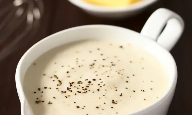 Sauce béchamel onctueuse, préparée avec de la fécule de maïs et assaisonnée de poivre noir fraîchement moulu.
