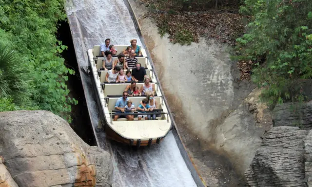 Bootsfahrt auf einer Wildwasserbahn, die durch eine üppige, grüne Landschaft führt. Die Menschen lachen und genießen die Fahrt auf der Isla Mágica.