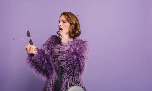 Chica con abrigo morado y maquillaje vibrante, lista para un evento.