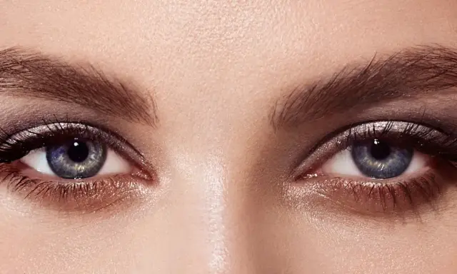 Ojos con un cautivador maquillaje con sombras azules y plateadas, realzados por pestañas largas y definidas.