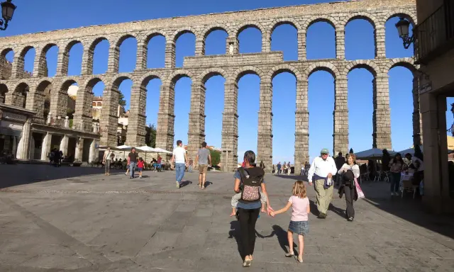 Familia pasea bajo el Acueducto de Segovia, un lugar ideal que ver en Segovia con niños.