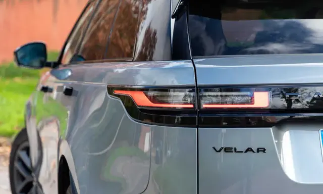 Detalle trasero de un Range Rover Velar plateado, mostrando sus luces LED y el emblema. Sus dimensiones son ideales para la ciudad y la aventura.