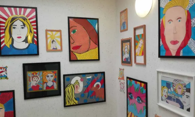 Bunte Pop-Art-Bilder, entstanden im Kunstunterricht, zieren die Wand. Porträts von Frauen im Comic-Stil, kräftige Farben und Linien.