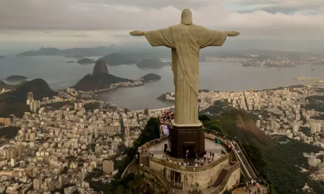 Majestatyczny pomnik Rio de Janeiro Jezus wita turystów, rozpościerając ramiona nad tętniącym życiem miastem i zatoką.