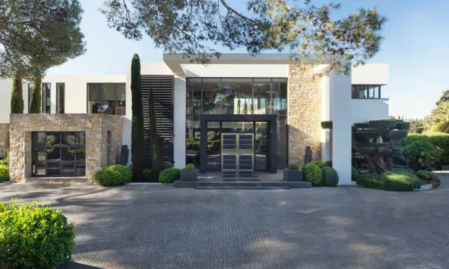 Une villa moderne avec des pierres apparentes et de grandes baies vitrées, parfaite pour construire une maison bioclimatique.