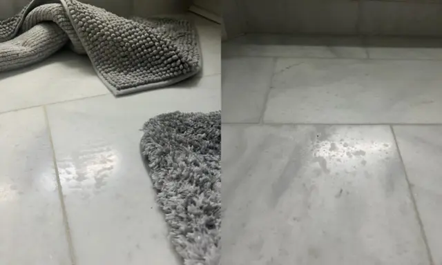 Grå badrumsmattor på marmorgolv. Vattenfläckar syns på golvet, vilket indikerar behov av marmor polering för att återställa glansen.