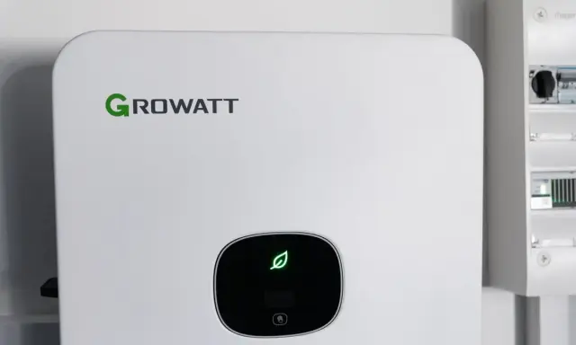 Vit Growatt-enhet med grön löv-symbol, del av ett modernt batterisystem för energilagring.