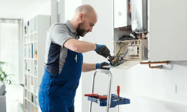 Técnico revisa el cableado interno de una caldera, mostrando cómo funciona.