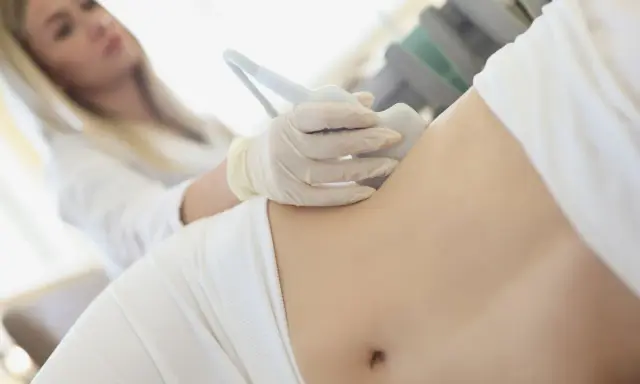 Ärztin untersucht Bauch einer Frau mit Ultraschall, um Schmerzen linke Seite Taille zu diagnostizieren.