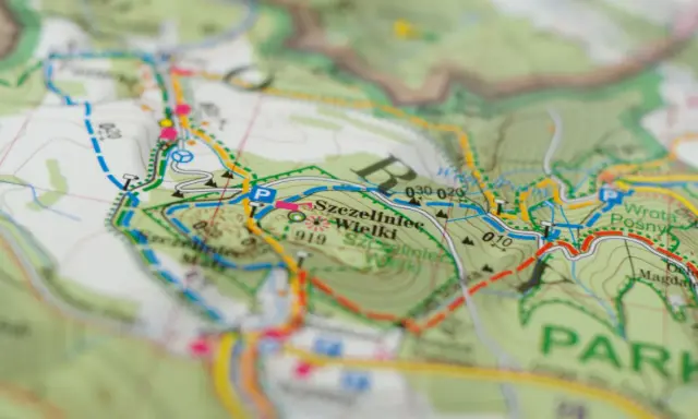 Mapa turystyczna z zaznaczonym szlakiem czerwonym, który oznacza najdłuższą trasę. Widoczne nazwy miejscowości i terenów.