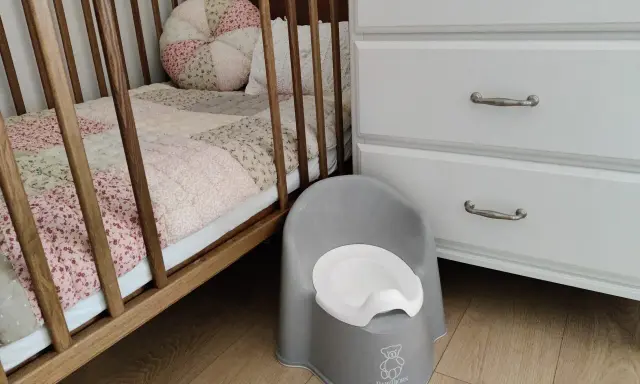 Szara nocniczka BabyBjörn obok łóżeczka. Czas na rozwiązanie problemu z odpieluchowaniem 3 latka.
