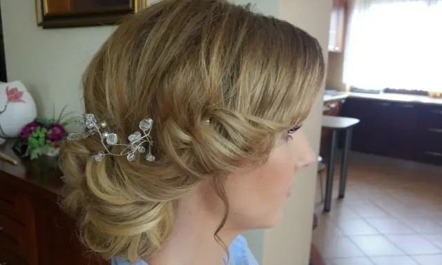 Eleganckie fryzury ślubne dla cienkich włosów: delikatny kok z kryształową ozdobą.